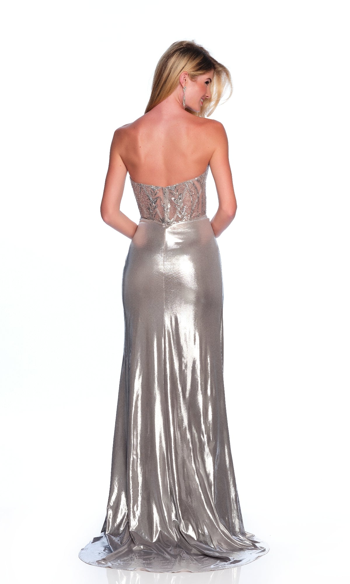 A woman stands with her back to the camera, wearing the Dave & Johnny 12326 Strapless Silver Prom Dress featuring a fitted bodice, shiny flowing skirt, and dramatic thigh-high slit.